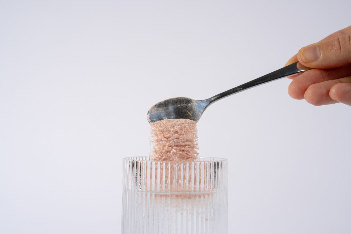Scoop of Anomaly powder over a glass
